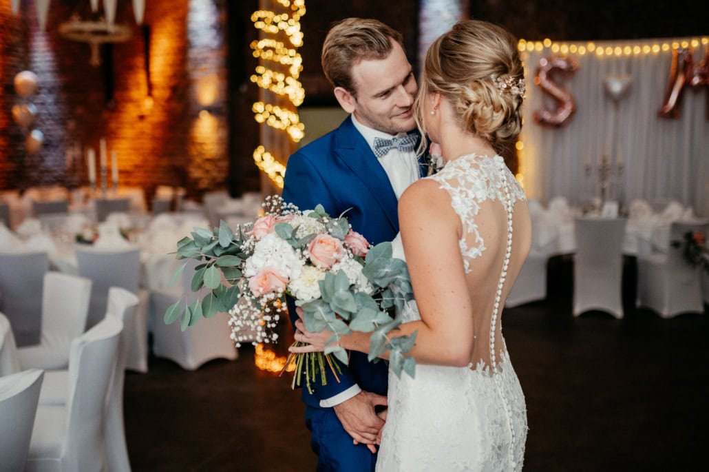 Hochzeitspaar im festlichen Ambiente mit Blumenstrauß und romantischer Dekoration.
