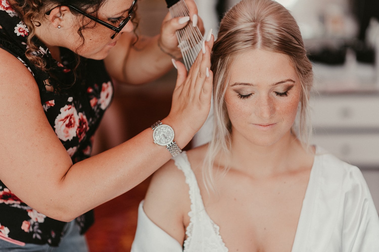 Friseurin macht der Braut eine Hochsteckfrisur vor der Hochzeit.