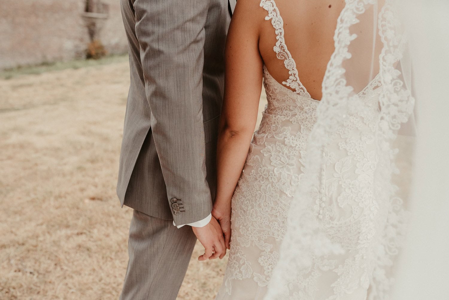 Hochzeitspaar hält Händchen im Freien, Nahaufnahme der Hände bei Sonnenuntergang.