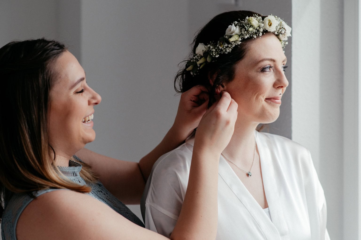 Braut wird für Hochzeit vorbereitet, trägt Blumenkranz im Haar.