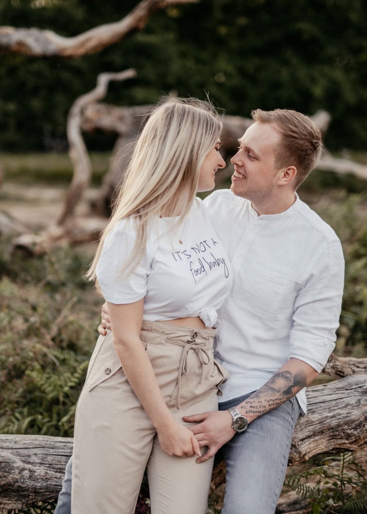 Liebespaar beim Fotoshooting im Naturraum mit dichtem Grün im Hintergrund.