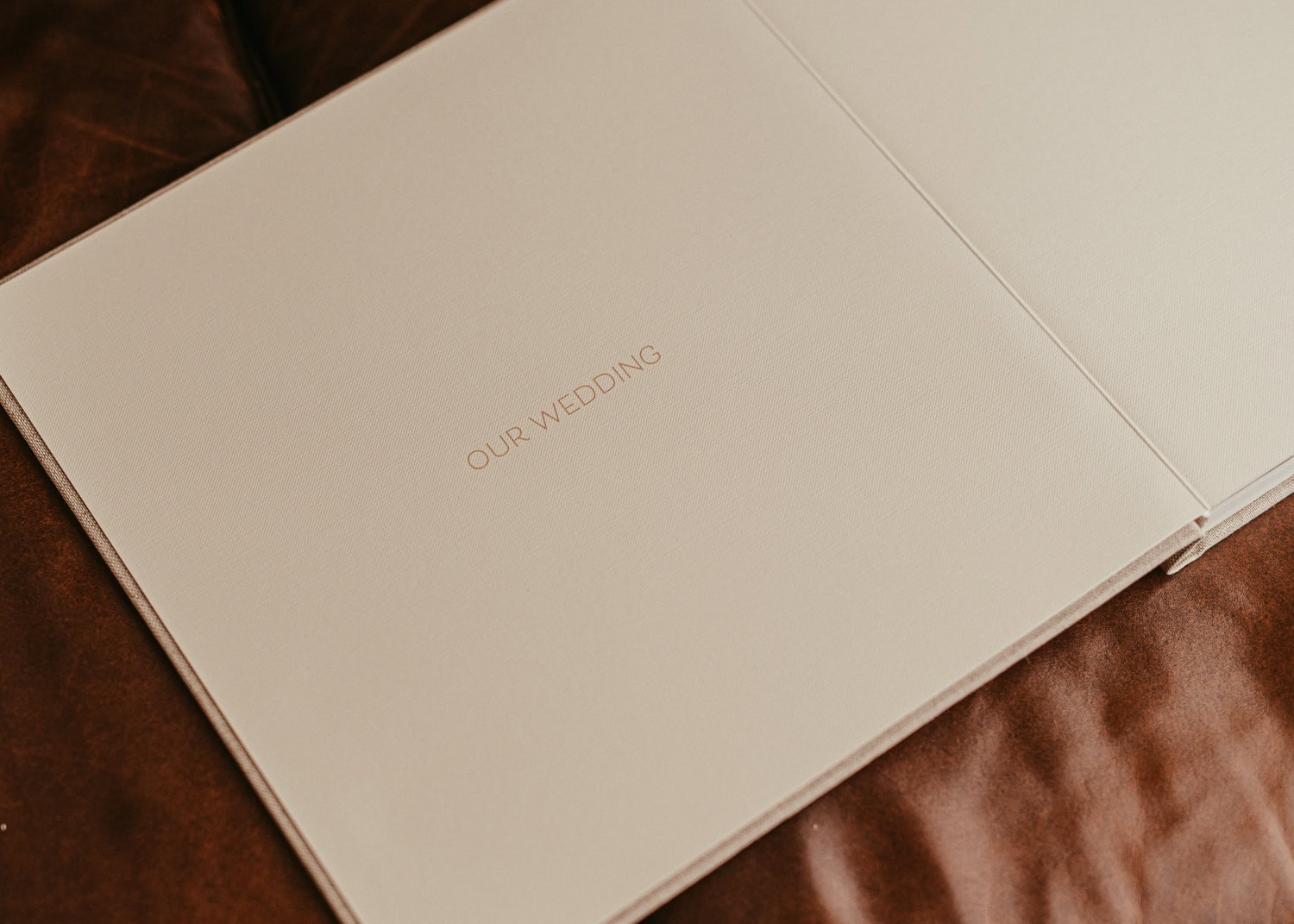 Hochzeitseinladungskarte mit goldener Schrift "Our Wedding" auf cremefarbenem Hintergrund.