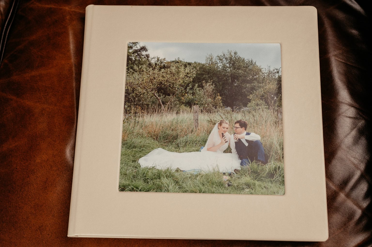 Hochzeitsfoto auf weißem Fotobuch mit Braut und Bräutigam im Grünen.