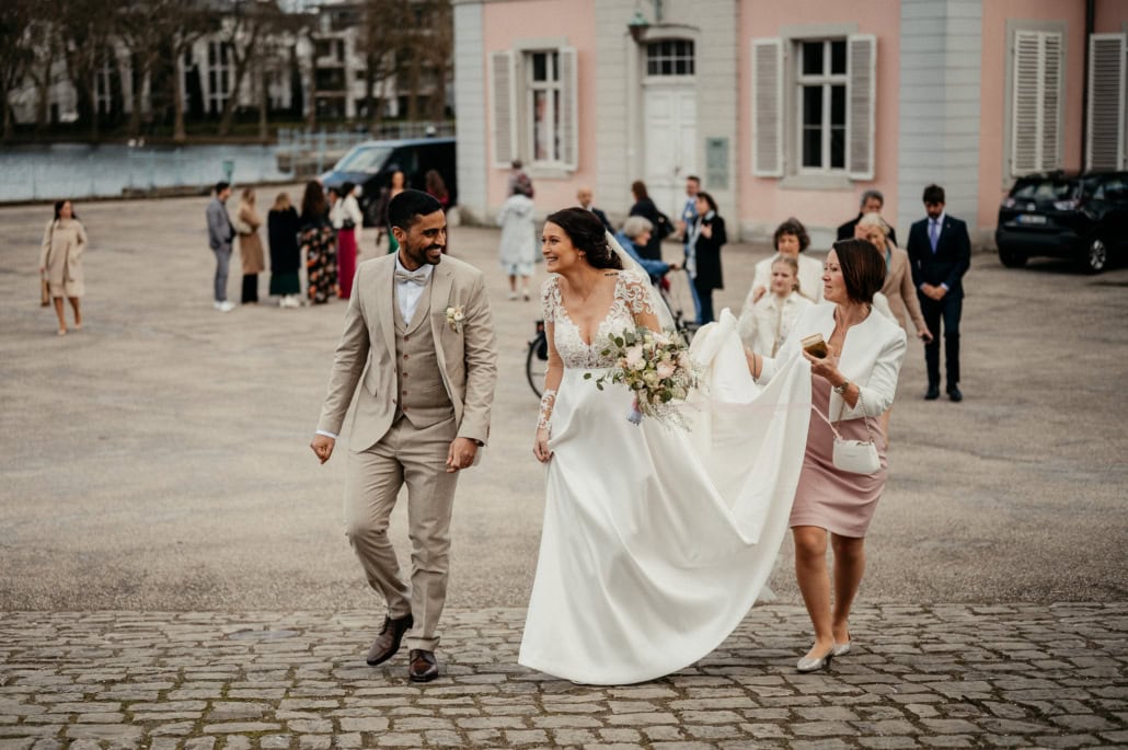 Brautpaar mit Gästen bei Hochzeit im Stadtzentrum, historische Gebäude im Hintergrund.