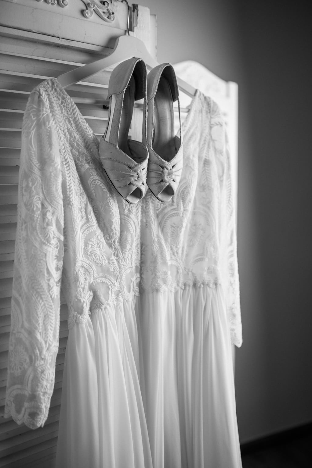 Elegantes weißes Hochzeitskleid mit Spitzenärmeln und Schleifen an den Schuhen.
