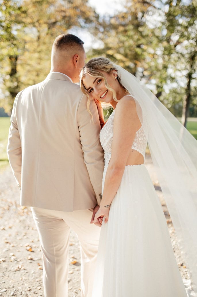 Hochzeitsfoto eines glücklichen Paares im Park, die Braut lächelt in die Kamera, während der Bräutig.