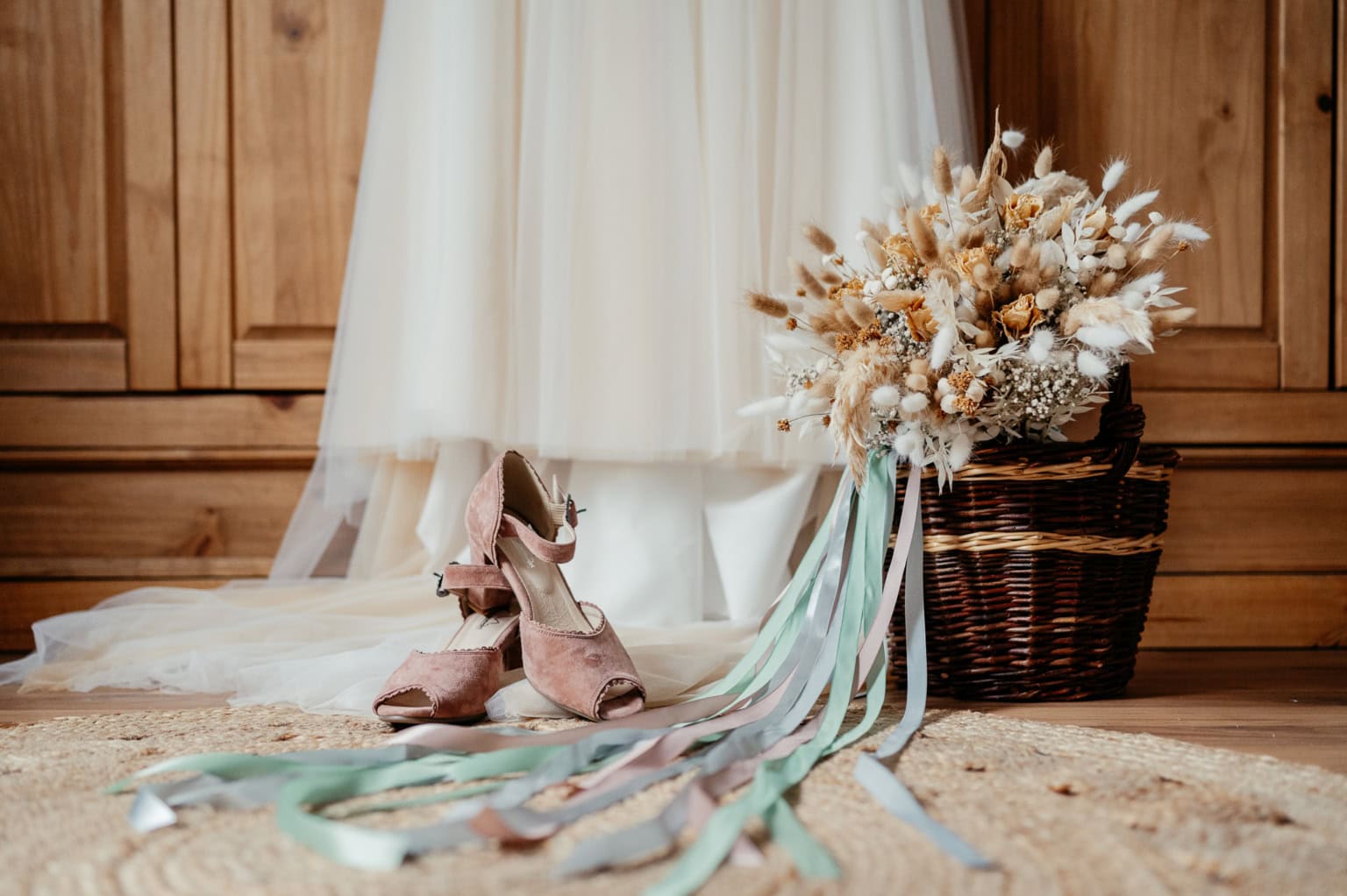 Blumenstrauß mit Ballettschuhen und Schleifen vor Holzschrank.