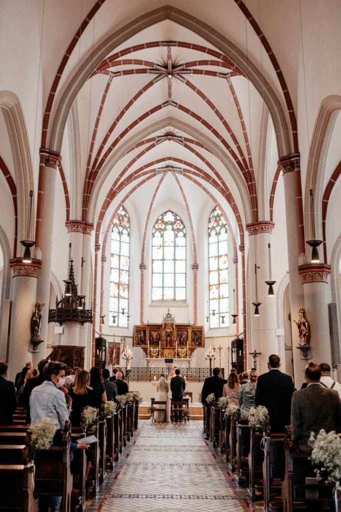 Hochzeitsreportage in einer Kirche mit Brautpaar und Gästen.