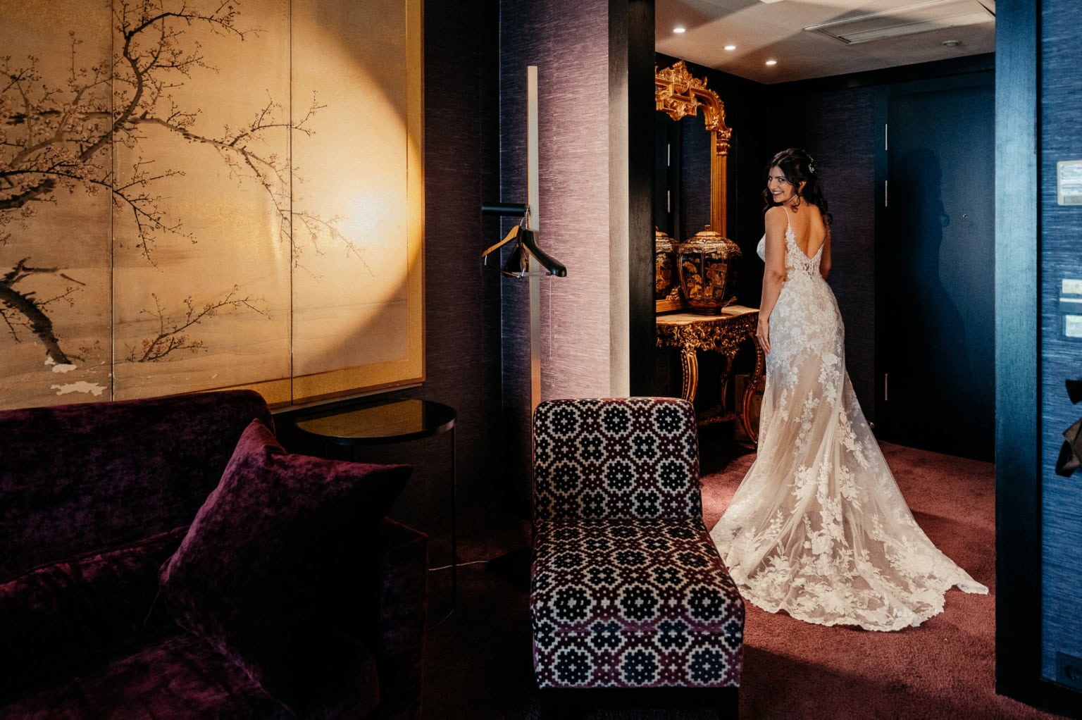 Braut in einem eleganten, weißen Hochzeitskleid im Hotelzimmer.