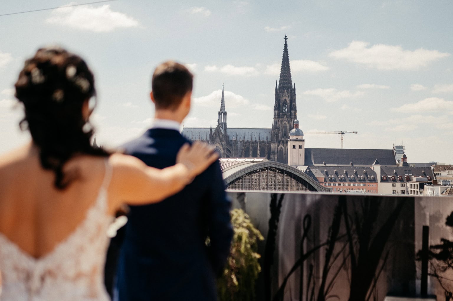 Braut und Bräutigam auf dem Dach mit Blick auf den Kölner Dom bei Sonnenuntergang.