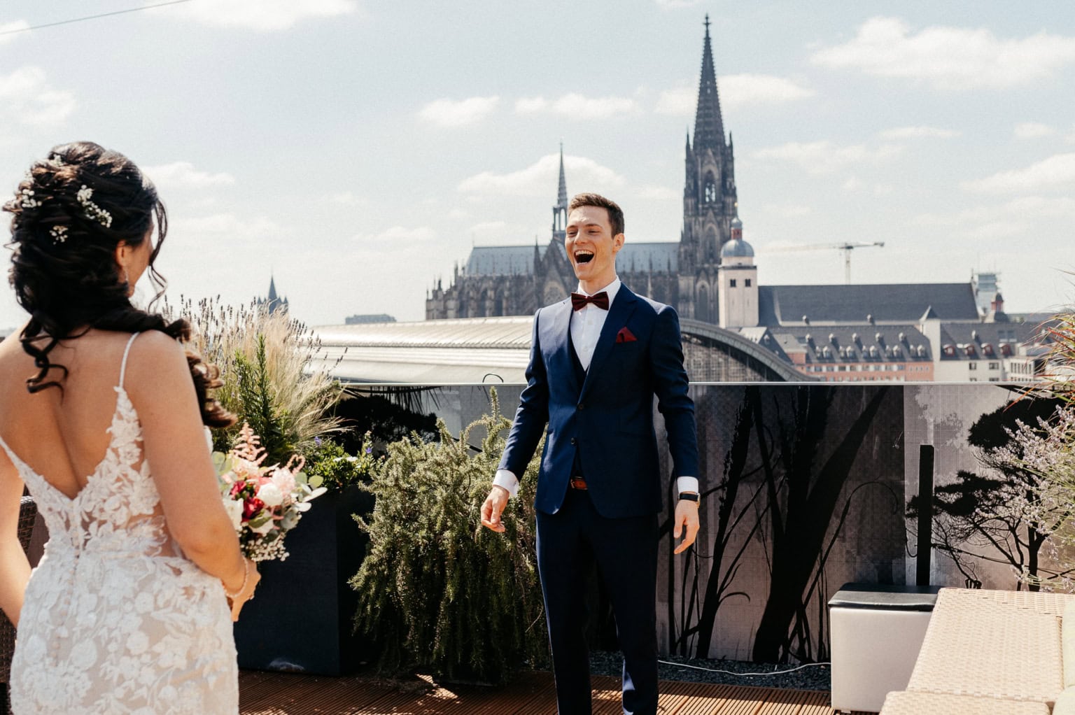 Hochzeitspaar auf der Dachterrasse mit Blick auf den Dom und die Stadt im Hintergrund.