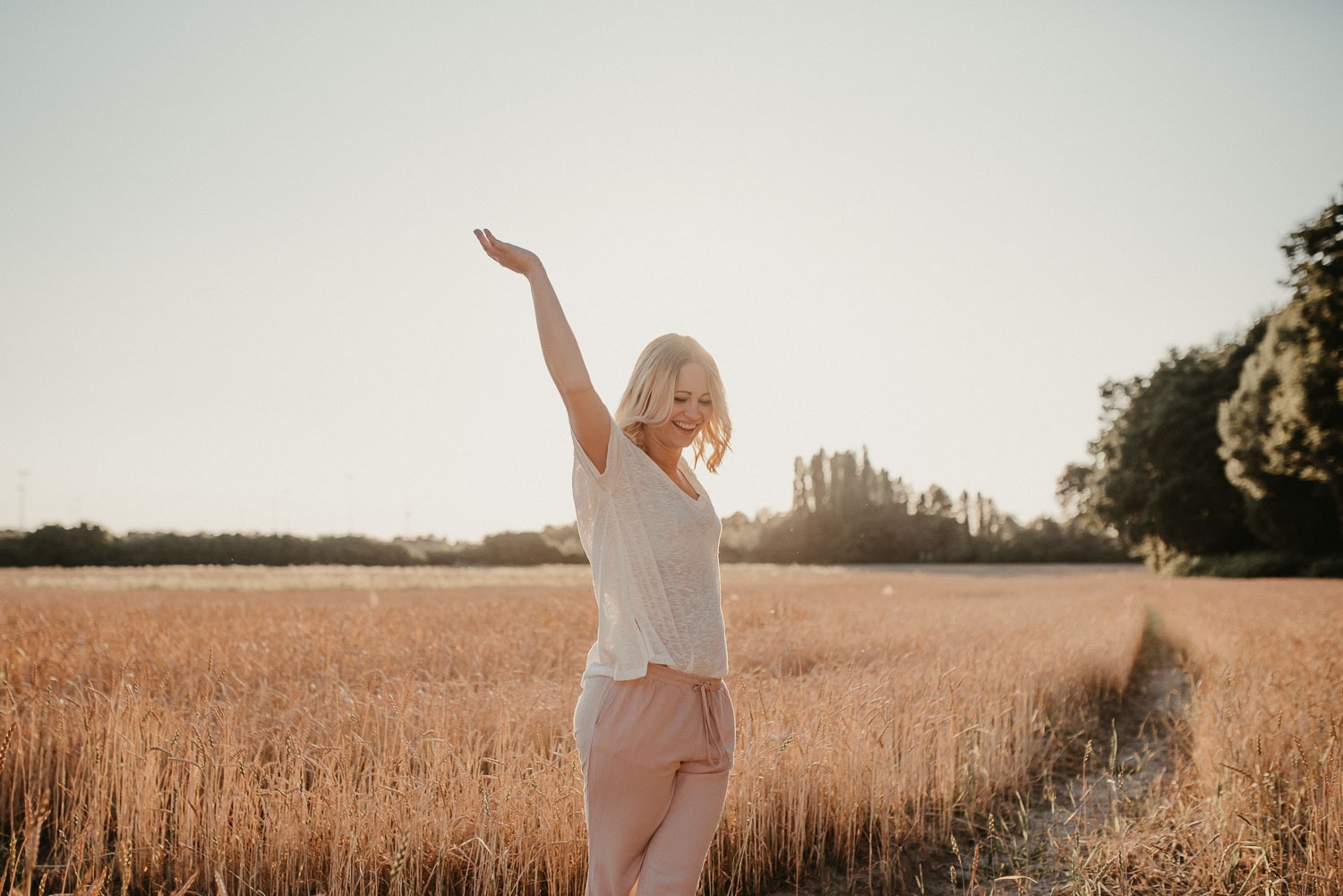 Frau genießt die Natur im goldenen Sonnenlicht auf einem Feld.
