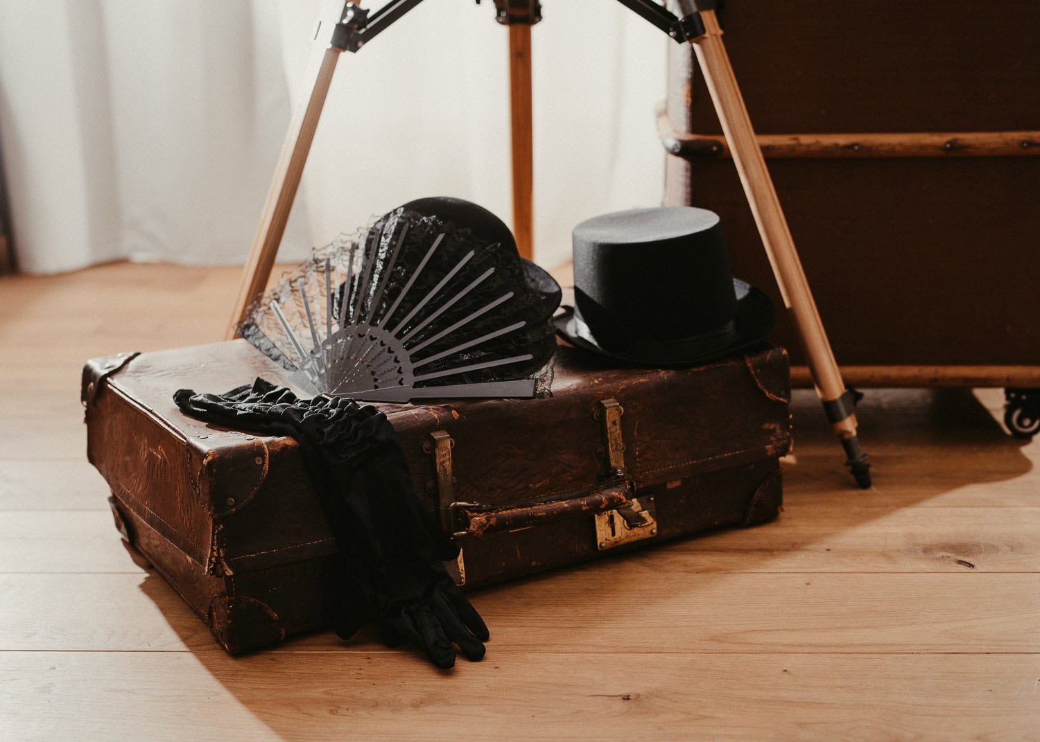 Vintage Accessoires auf altem Koffer, Kamera-Stativ im Hintergrund.