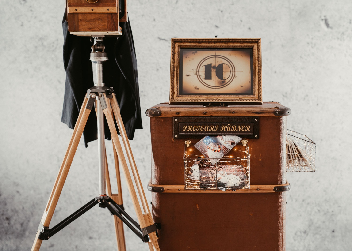 Kamera, Holztruhe und Filmprojektor im Vintage-Stil vor grauer Wand.