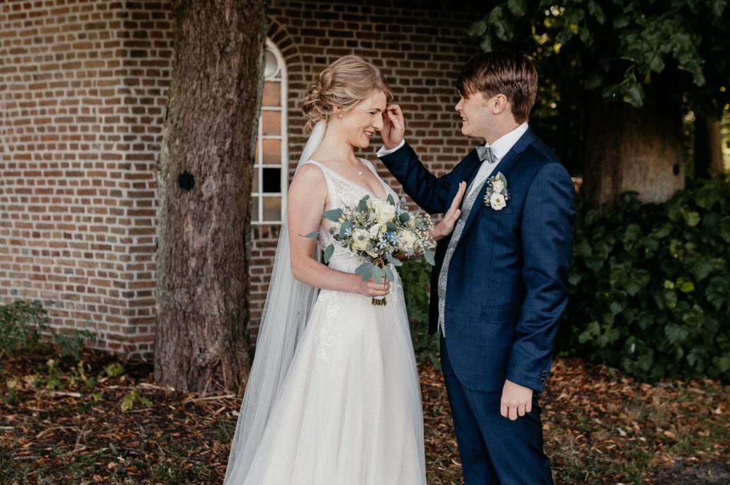 Braut und Bräutigam bei ihrer Hochzeit im Garten, liebevoll umarmend.